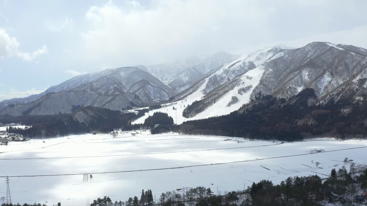 el avión no tripulado captura con gracia una vista aérea hipnótica del valle de hakuba y el vasto campo de nieve en japón durante el invierno, mostrando un paisaje cautivador adornado con nieve prístina y bosques exuberantes