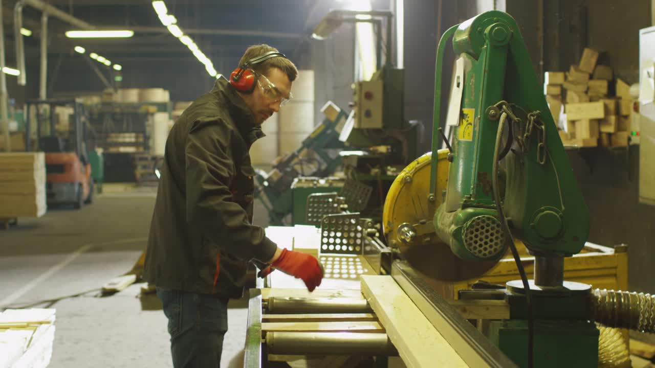 el trabajador de la fábrica de madera está cortando madera con una sierra circular.
