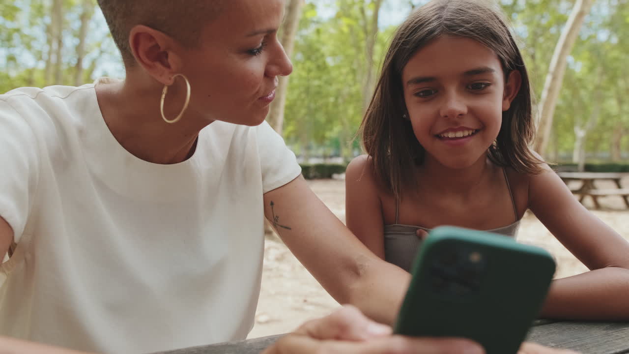 Mother and Daughter Using Phone in Park