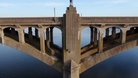 slow aerial descending shot features beautiful concrete bridge architecture and design pattern revealing calm blue river water