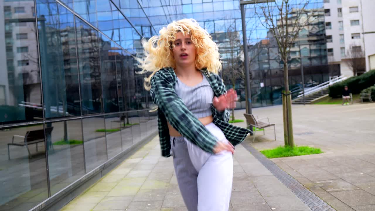 Woman with curly hair in plaid shirt poses in urban setting