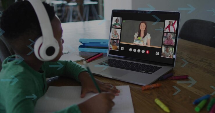School-age boy starting note-taking in home study after virtual teacher appearing on laptop screen