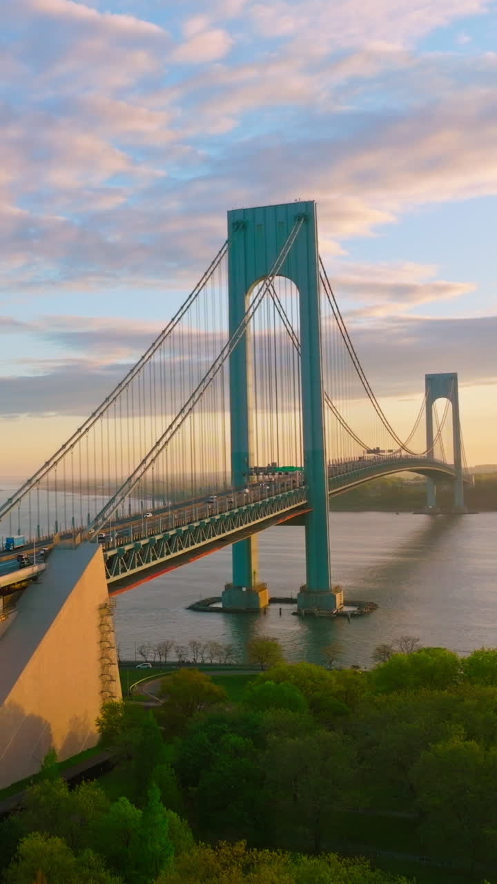Quickly moving cars along the huge beautiful Bridge. Bronx-Whitestone Bridge crossing East River at the backdrop of amazing sky. Vertical video