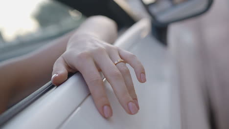 woman's hand with ring, car window