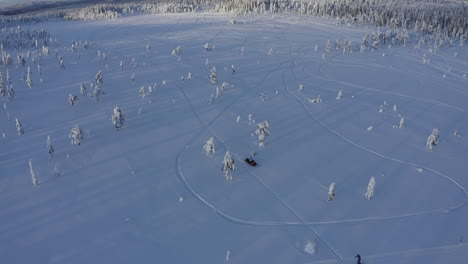 toma aérea de drones al atardecer de un viajero montando una moto de nieve en la naturaleza de suecia