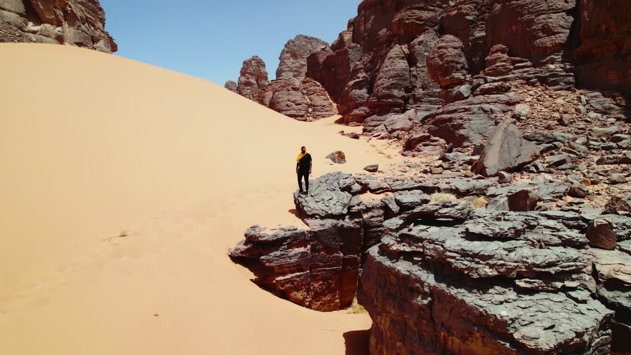 vista aérea de un hombre de pie en la formación rocosa en el desierto de djanet, argelia