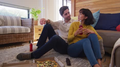 video de una feliz pareja diversa bebiendo cerveza y hablando en la sala de estar