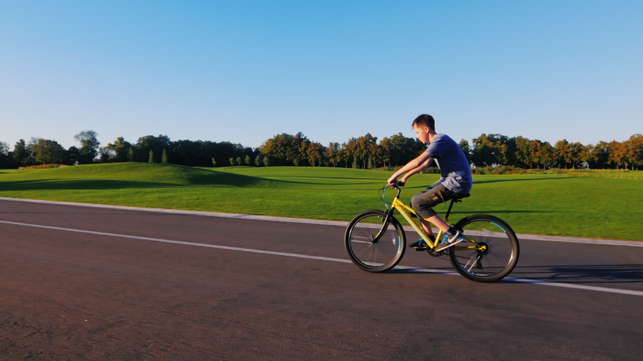 십대는 녹색 골프 코스를 배경으로 평평한 길을 간다
