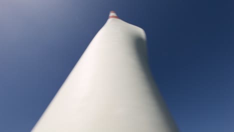 looking up at a towering wind turbine blade against a clear blue sky