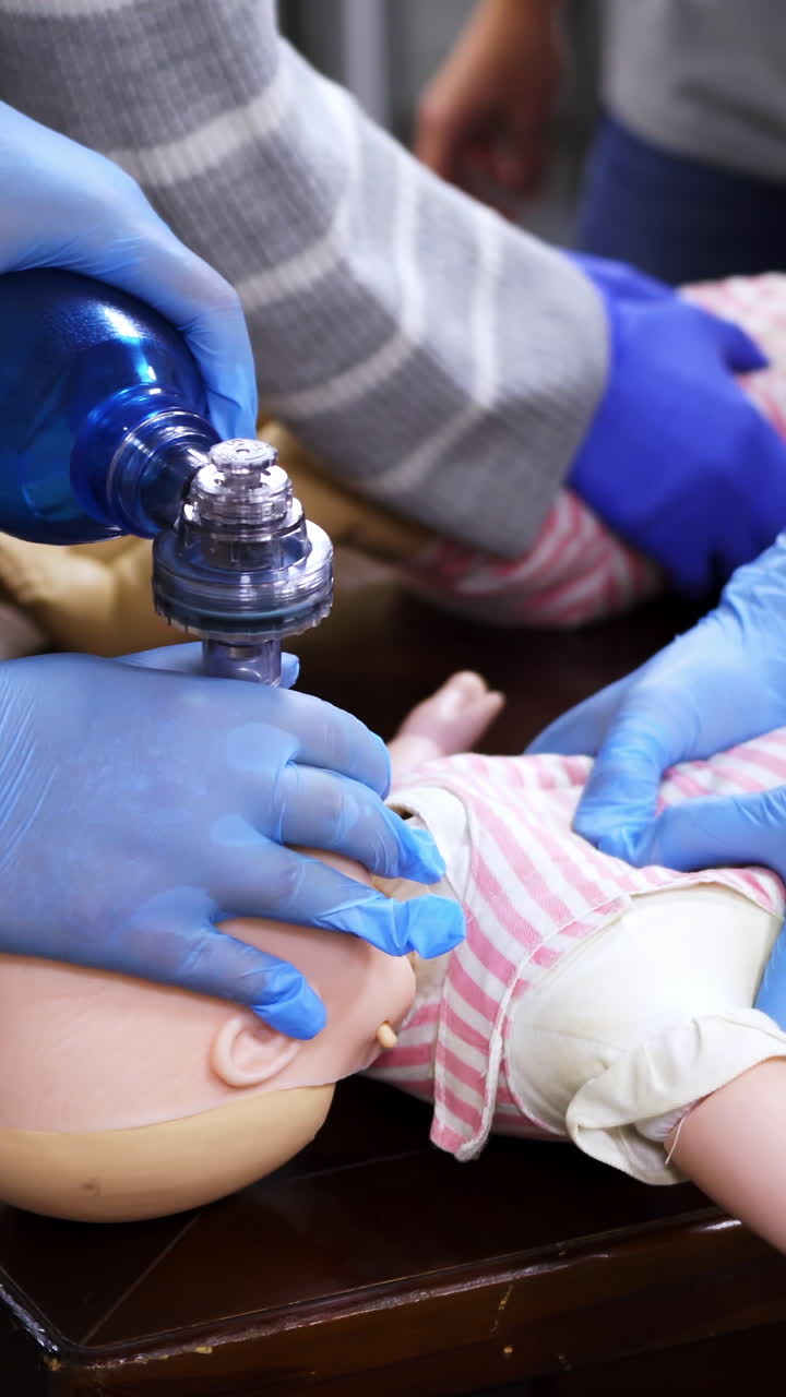 Teaching of cardiopulmonary resuscitation. Performing cardiopulmonary resuscitation on baby training doll. Vertical video