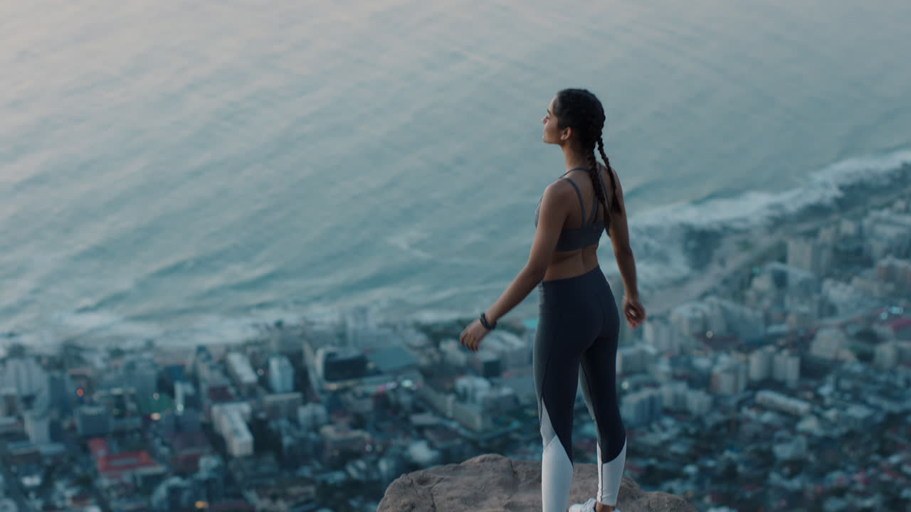 mujer independiente con los brazos levantados en la cima de la montaña celebrando el logro niña en el borde del acantilado mirando la hermosa vista al atardecer disfrutando de la aventura de viaje