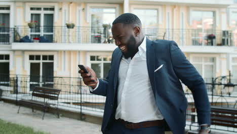 Cheerful-afro-man-receiving-good-news-on-the-phone-outside