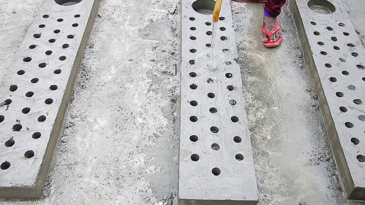 Indian mason worker pouring water over concrete to accelerate the hardening process, industrial construction scene