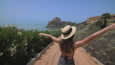 mujer caminando por un camino hacia un castillo en la playa