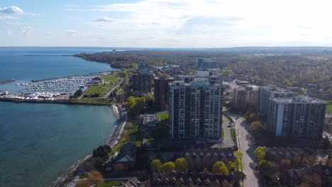 Aerial-shot-flying-next-to-Oakville-lakeshore-with-a-harbor-in-view-at-sunset