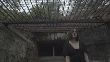 slow motion portrait of a goth girl inside exterior animal cage