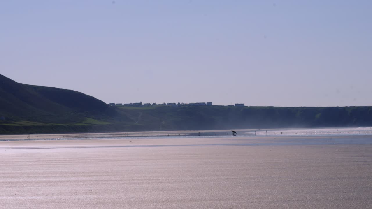 View Across Rhossili Bay Beach with Sea Mist and Surfers in Distance on Sunny Day in Wales UK 4K