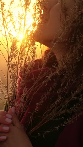 woman enjoying the sunset among dried plants