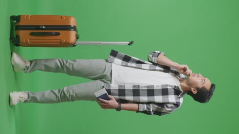 full body of asian male traveler with luggage and passport thinking about something and looking around while standing in the green screen background studio