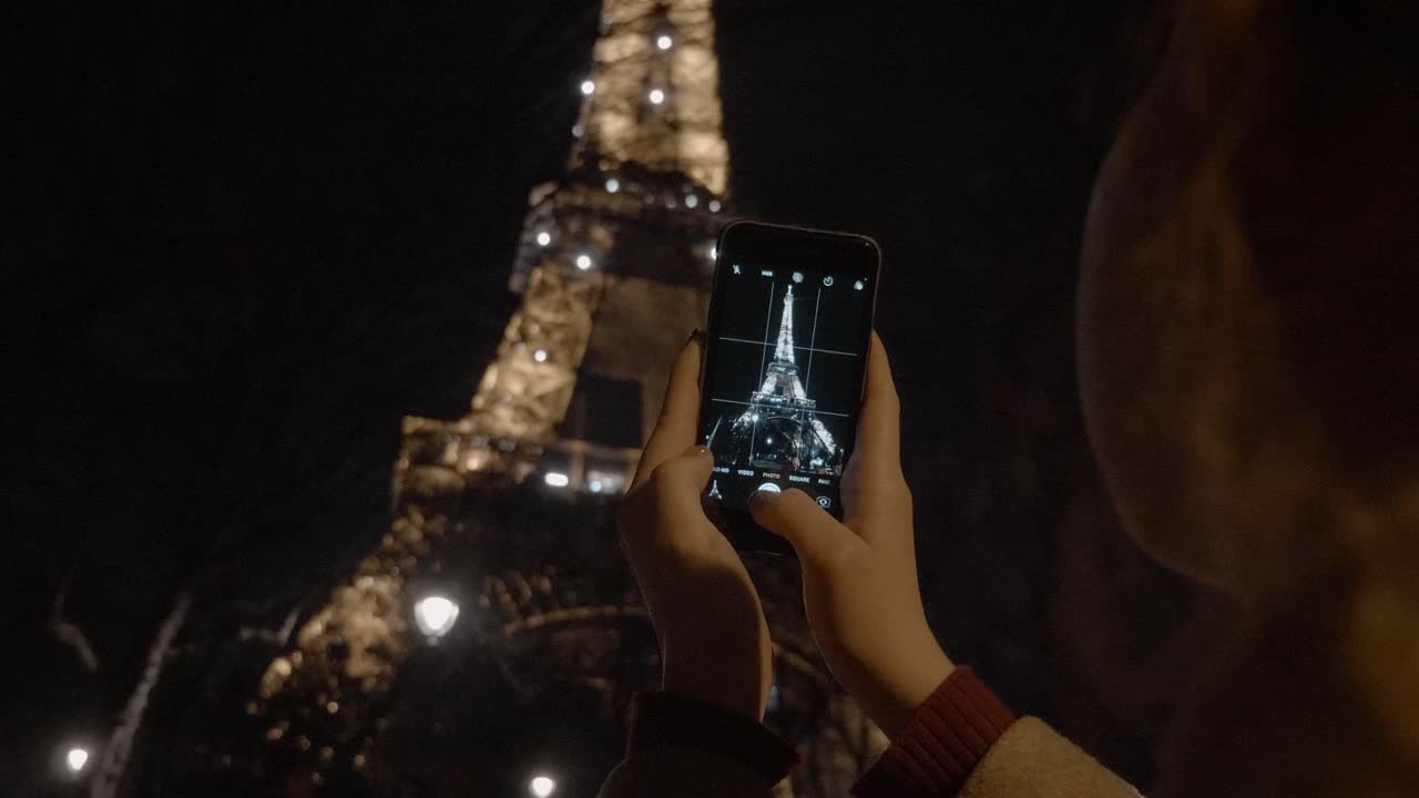mujer tomando fotos de la torre eiffel en parís, francia