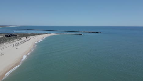 aerial-of-the-serene-beauty-of-Ilha-Deserta,-a-pristine-island-devoid-of-human-presence,-with-the-iconic-Lighthouse-Island-in-the-background-of-Faro,-Algarve,-Portugal