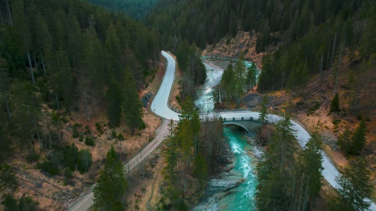 vuelo aéreo sobre un pintoresco río de montaña con agua azul fresca en los alpes bávaros austríacos por el sol de la tarde, fluyendo por un lecho de río a lo largo de árboles, bosques, una calle y colinas vistas por drones