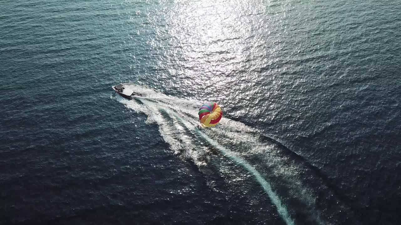 Luftfoto af en båd, der trækker en faldskærm i havet.