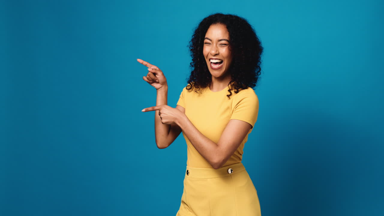 Woman in yellow outfit pointing on blue background