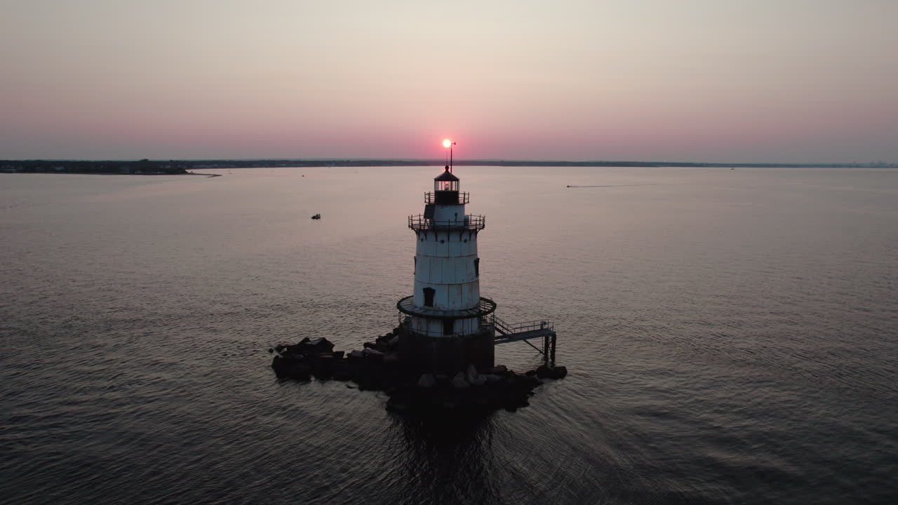 에어리얼 상승 비디오는 워릭, 리오의 코니 ⁇  포인트 등대 뒤에서 일몰을 보여줍니다.