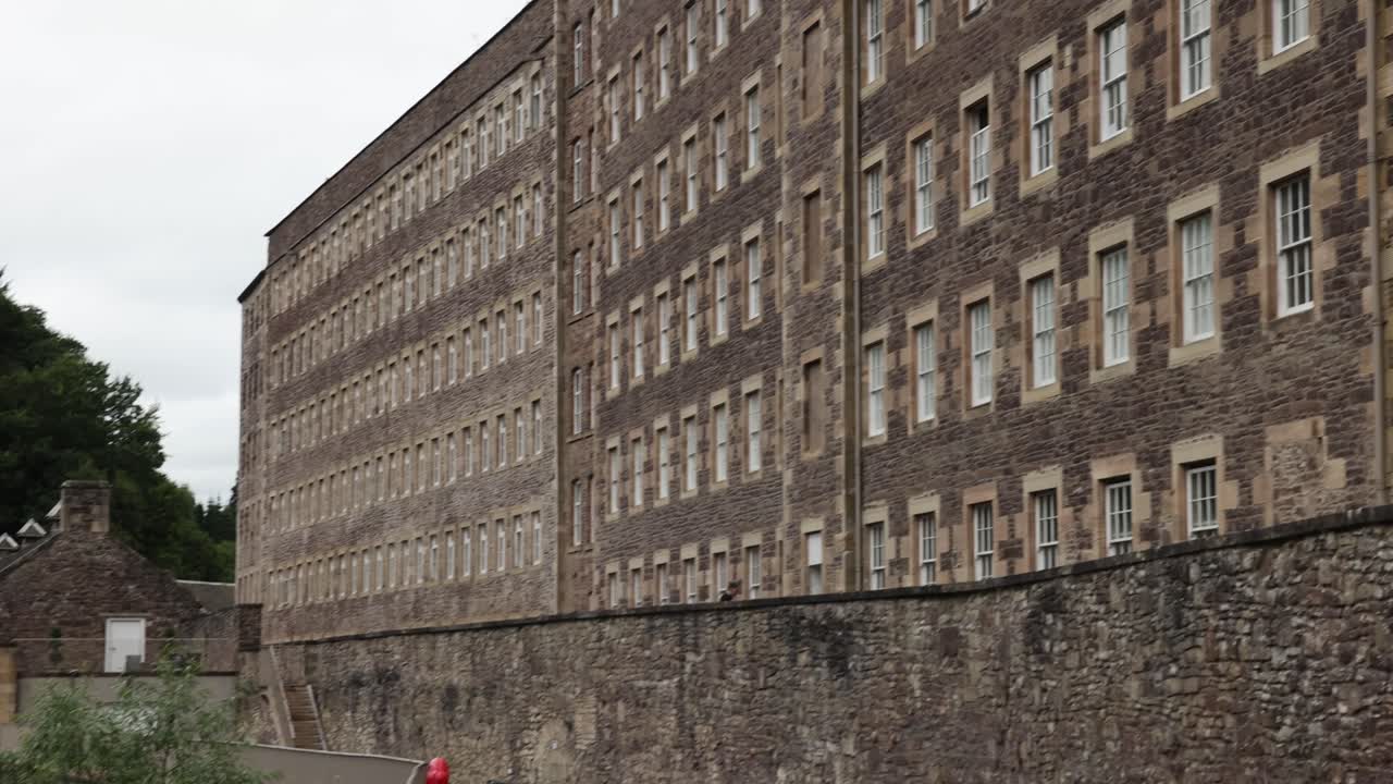 Slow establishing shot of windows on old tenement buildings at New Lanark