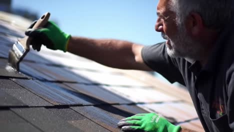 a professional meticulously applies a protective coating to shingles on a rooftop under bright sunlight. the detailed work ensures long-lasting durability and resistance against the elements.