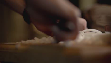 cook mincing white onions into the wooden chopping board