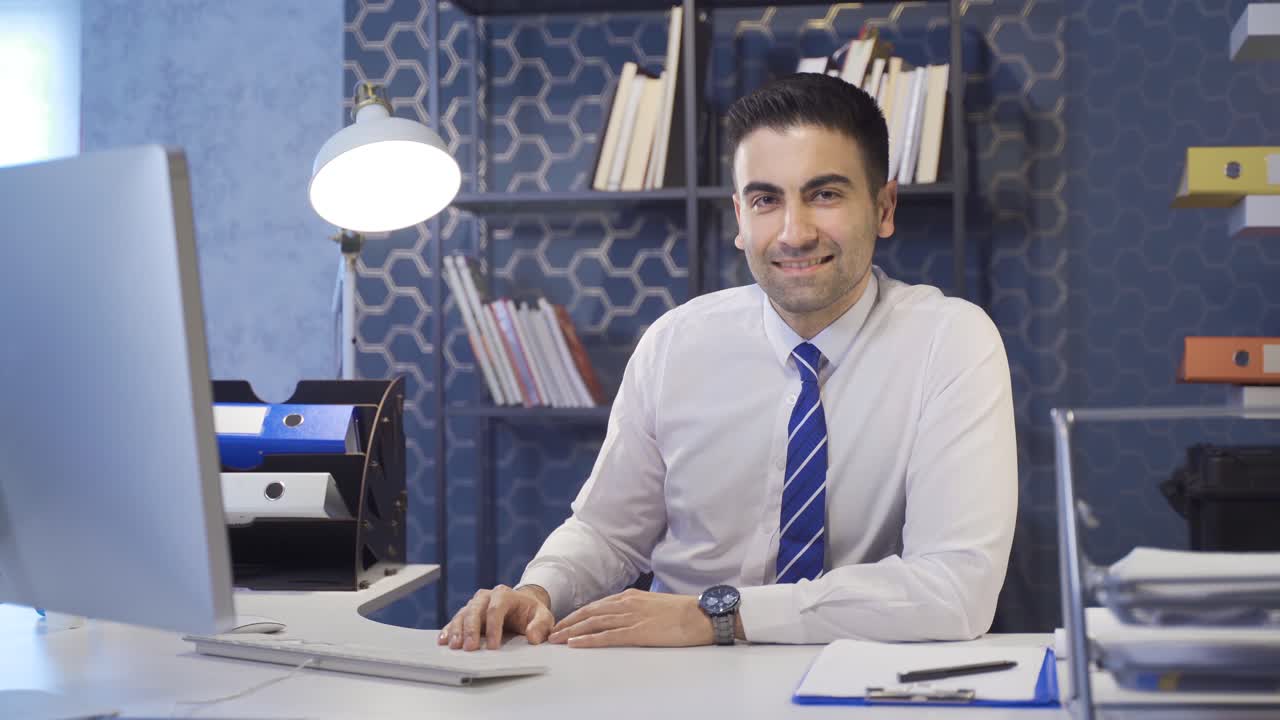 Uomo d'affari sorridente e affascinante che guarda la telecamera in ufficio.