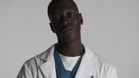 médico afroamericano pensativo en el fondo gris.