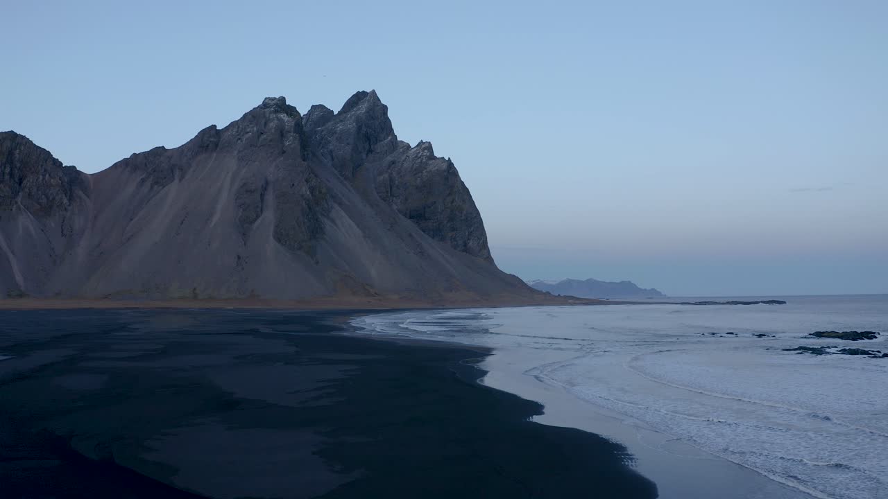 Fremadgående luftoptagelse over vulkansk sort strand og Vestrahorn-bjerget i baggrunden - Tidlig morgen på Island.