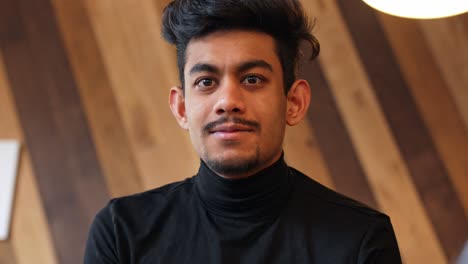 Guy-in-a-closed-neck-sweater-staring-at-the-camera-and-winks-with-his-right-eye,-static