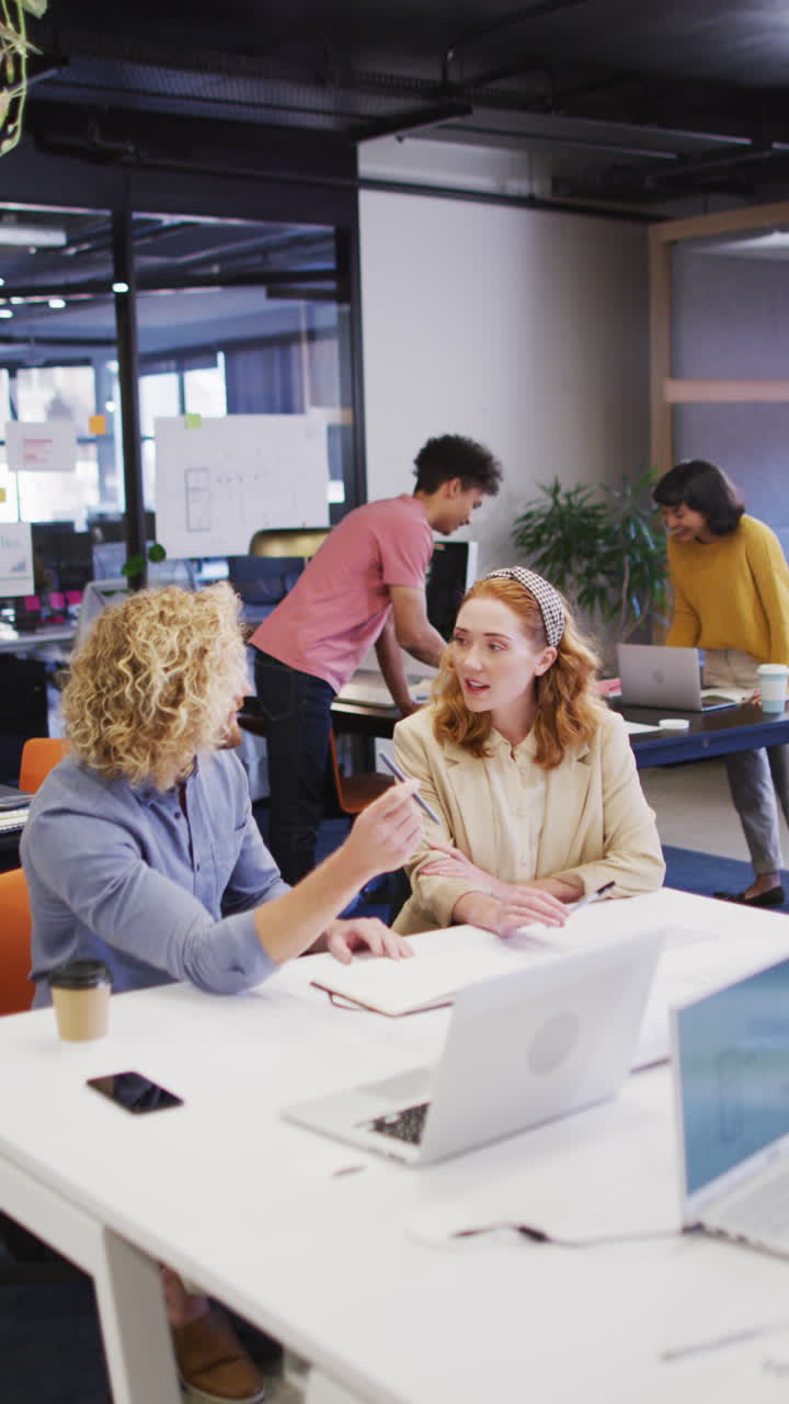 Vertical video of diverse business people discussing work at office