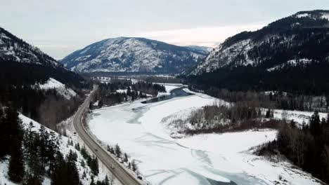 Autos-Fahren-Auf-Dem-Yellowhead-Highway-5,-Umgeben-Von-Schneebedeckten-Bergen-Und-Einem-Wunderschönen-Wald-In-Little-Fort,-BC:-Eine-Luftaufnahme-Mit-Rückwärtsflug