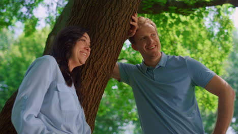 lovely couple talking lean on tree close up. pretty wife laughing with husband.