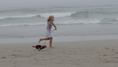 chica corriendo con el perro en la playa