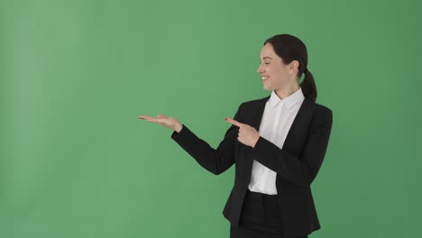 businesswoman pointing at green background