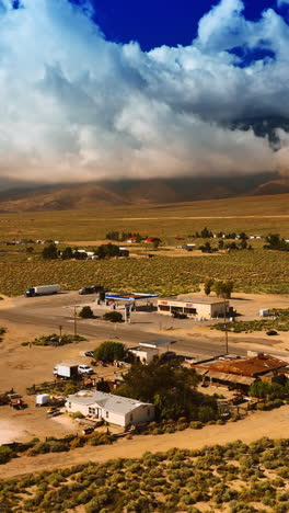 approaching the village in the desert of death valley, california. some households are scattered in the area around the highway. mountains hidden by clouds at backdrop. vertical video