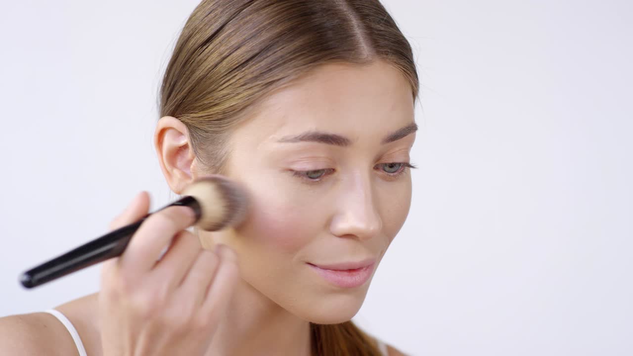 una mujer hermosa sonriendo y poniéndose maquillaje.