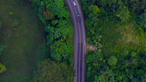 Cars-driving-on-road-surrounded-by-green-and-lush-forest,-Samana