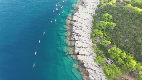 aerial view of a group of tourists on a kayak tour passing by the coast of lokrum island near dubrovnik on the adriatic coastline of croatia