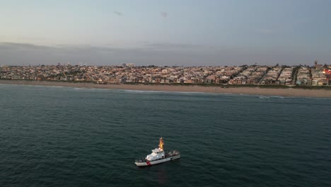 Aerial-View-Of-Coast-Guard-Boat-Anchored-Near-Mainland-Of-Beachfront-City-In-USA