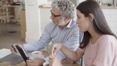 bearded ceo pointing at tablet screen with finger and showing to his colleague