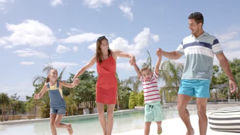 una feliz familia caucásica tomándose de la mano en la piscina de la casa de la playa.