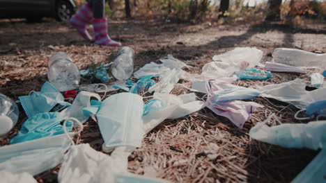 los pies del niño con botas caminan por el bosque pasando por un montón de basura