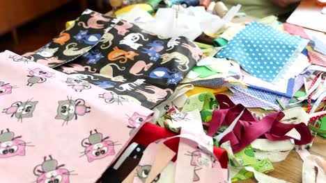 variety of colorful fabric pieces stacked on table of seamstress